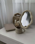 Nordic cloud-shaped vanity mirror on a table with book, cup, and candles, enhancing home decor with modern elegance and free shipping.