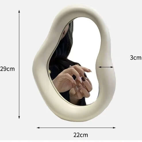 Cream-colored Nordic asymmetric mirror, 29x22 cm, showing reflection of a person’s hand, with free shipping.