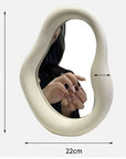 Cream-colored Nordic asymmetric mirror, 29x22 cm, showing reflection of a person’s hand, with free shipping.