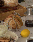 Elegant stainless steel toast holder with fresh bread, perfect for a sophisticated breakfast setup.