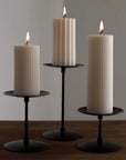 Three Retro Iron Candlesticks at different heights with ribbed pillar candles, lit