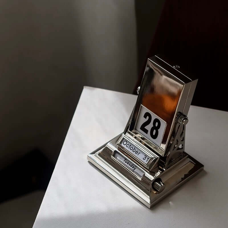 Nordic Rotating Desk Calendar with metallic finish showing October 28, minimalist design, tabletop date keeper, 7x8x10.5cm.