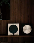 Two Bauhaus Aura Bedside Lamps, black base and brushed silver base, on a wooden shelf