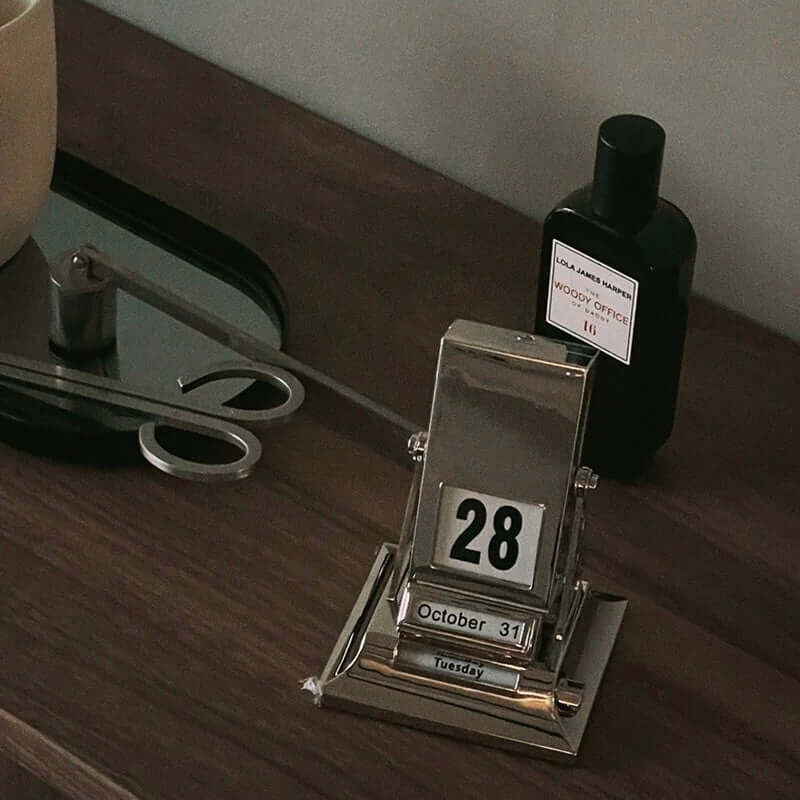 Timeless Rotating Desk Date Keeper on a wooden desk next to decor items, showcasing minimalist elegance and functionality.