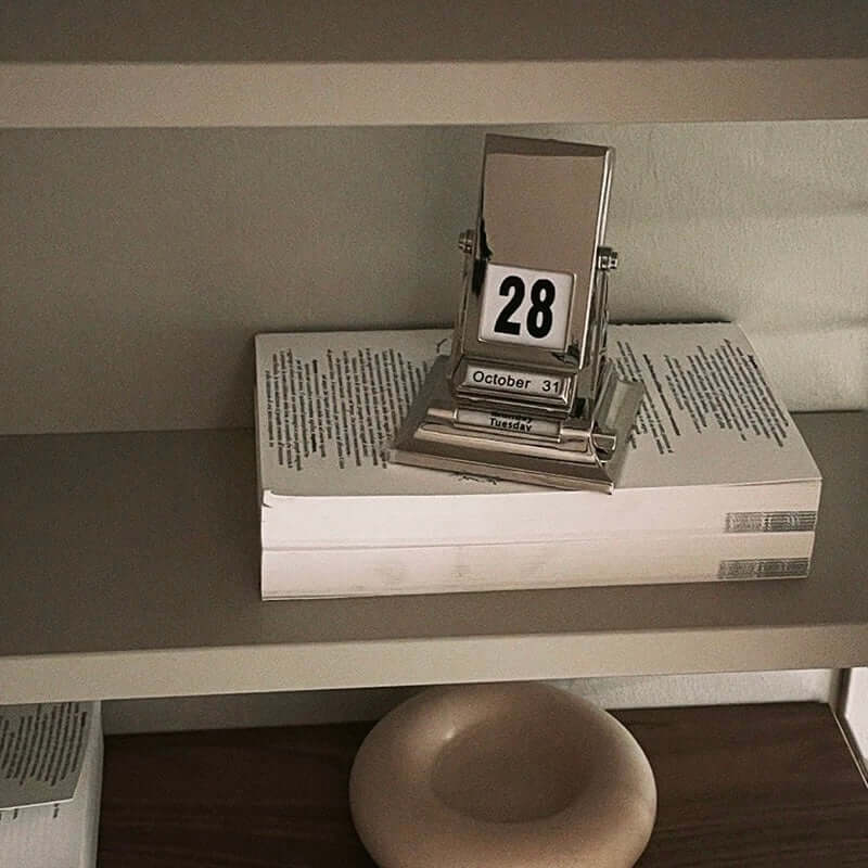 Rotating desk date keeper on a shelf, showcasing minimalist elegance and functionality in a sleek Nordic design.