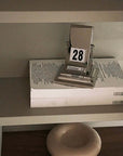 Rotating desk date keeper on a shelf, showcasing minimalist elegance and functionality in a sleek Nordic design.