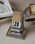 Elegant Nordic Rotating Desk Calendar with stainless steel finish, showcasing October 28th date, minimalist design on a desk.