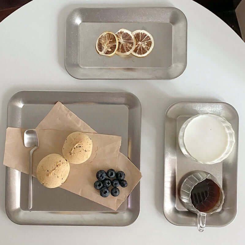 Urban Chic stainless steel serving trays displaying desserts and beverages on a minimalist table setting.