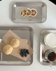 Urban Chic stainless steel serving trays displaying desserts and beverages on a minimalist table setting.