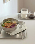 Stainless steel serving tray set with food and drink, showcasing urban chic minimalist design on a white table.