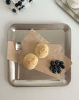 Stainless steel serving tray with cookies, blueberries, and spoon, showcasing minimalist urban chic design.