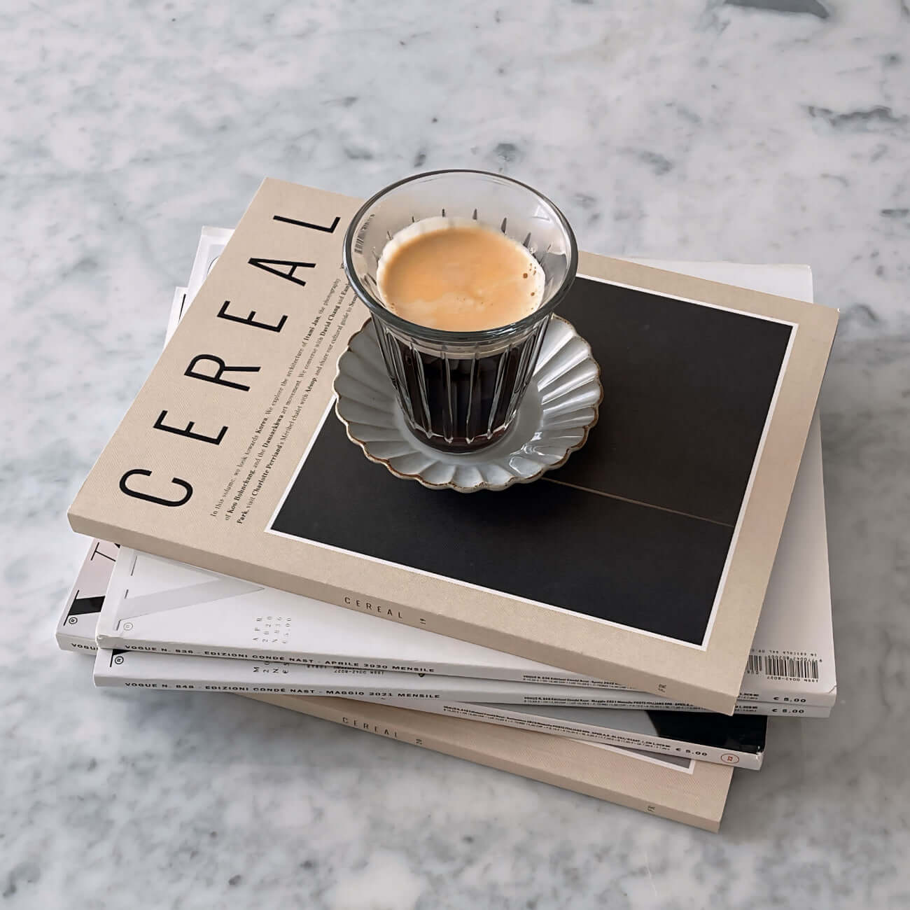 Zinc glass cup on Marumitsu Barbarie saucer, placed on stacked Cereal magazines on a marble table.
