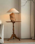 Custom-crafted wooden lamp on a wooden table in a cozy living room setting, showcasing unique design and warm lighting.