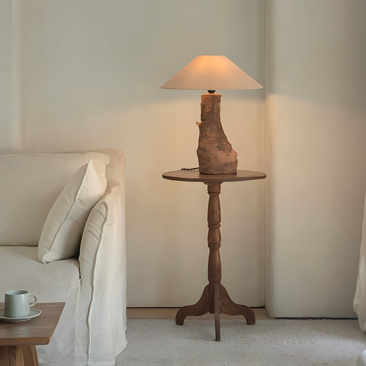 Custom-crafted wooden lamp on rustic side table next to white sofa in cozy living room setting.