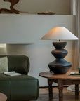 Stylish Hill Table Lamp with a linen shade and ceramic body on a wooden table in a cozy living room setting.