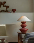 Cozy living room with elegant ceramic pot table lamp featuring a linen shade on a wooden side table, enhancing warm ambiance.