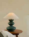 Elegant Hill Table Lamp with a linen shade and ceramic base, adding artisanal grace to a room, placed on a wooden table.