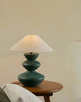Elegant Hill Table Lamp with a linen shade and ceramic base, adding artisanal grace to a room, placed on a wooden table.