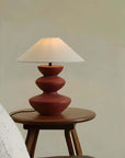Hill Table Lamp with linen shade and ceramic base, displayed on a wooden side table in a cozy room setting.
