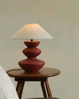 Hill Table Lamp with linen shade and ceramic base, displayed on a wooden side table in a cozy room setting.