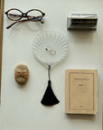 Lumière Shell Glass Dish holding rings, laid out with glasses, a comb and a book