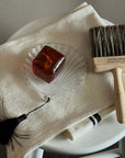 Lumière Shell Glass Dish with soap beside a wooden brush on a towel