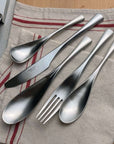 Elysian Stainless Steel Cutlery pieces on a striped linen napkin