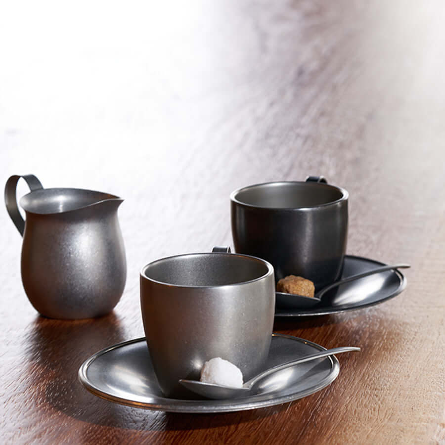 Vintage inox cup and saucer set with stainless steel finish, includes two cups with matching saucers on a wooden table.