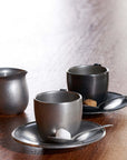 Vintage inox cup and saucer set with stainless steel finish, includes two cups with matching saucers on a wooden table.