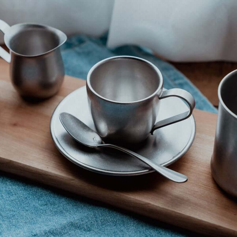 Vintage Inox stainless steel cup and saucer set with spoon on wooden board, elegant and dishwasher safe Japan-made design.