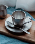 Vintage Inox stainless steel cup and saucer set with spoon on wooden board, elegant and dishwasher safe Japan-made design.