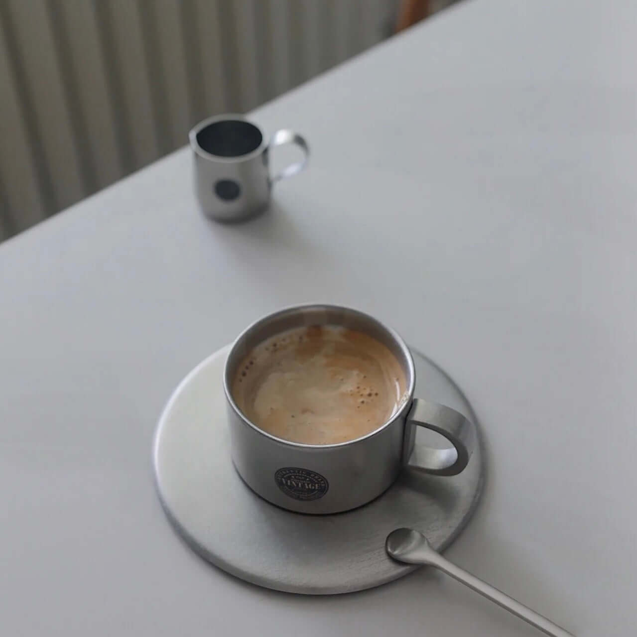 Stainless steel cup and saucer set with coffee, showcasing sleek design perfect for various occasions.
