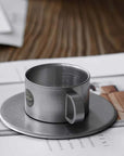Vintage INOX stainless steel cup and saucer, 90ml, on a table. Durable, chic design for versatile use. Dishwasher safe, made in Japan.