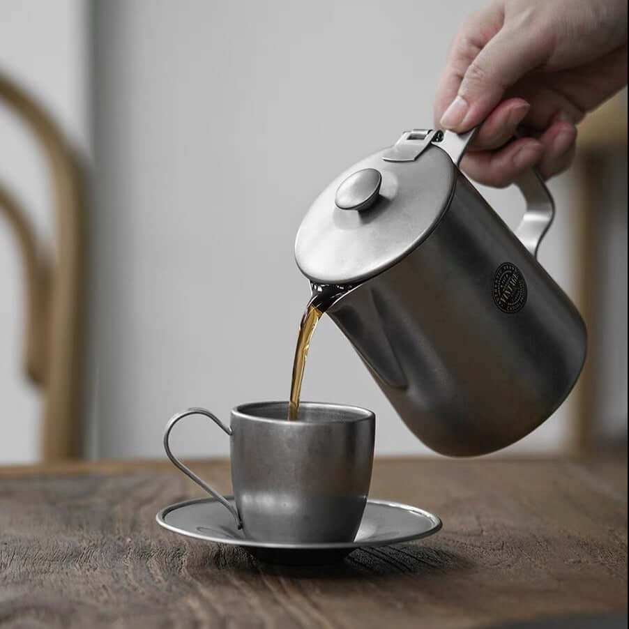Pouring coffee from VINTAGE INOX stainless steel cafe pot into matching cup, showcasing durable and chic design. Made in Japan.