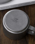 Vintage INOX stainless steel cup bottom view showing engraved details on wooden table.
