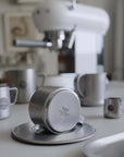 Vintage INOX stainless steel cup and saucer set on kitchen counter, showcasing durable and chic design with background kitchenware.
