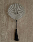 Lumière Shell Glass Dish with tassel on a stone surface, top view