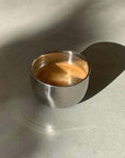 Stainless steel spherical cup with coffee on a sunlit surface