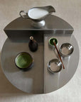 Elegant tea setup with cups and milk jug on a modern round tray, featuring a minimalist design and green tea presentation.