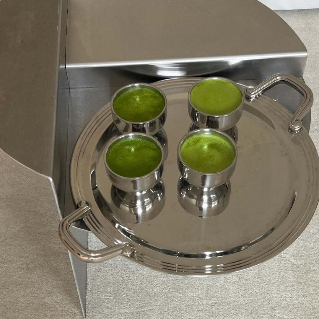 Stainless steel spherical cups with green drinks on a silver tray, showcasing elegance and style for serving beverages.