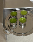 Stainless steel spherical cups with green drinks on a silver tray, showcasing elegance and style for serving beverages.