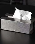 Steelform Tissue Box in raw brushed steel with tissues, on a black table