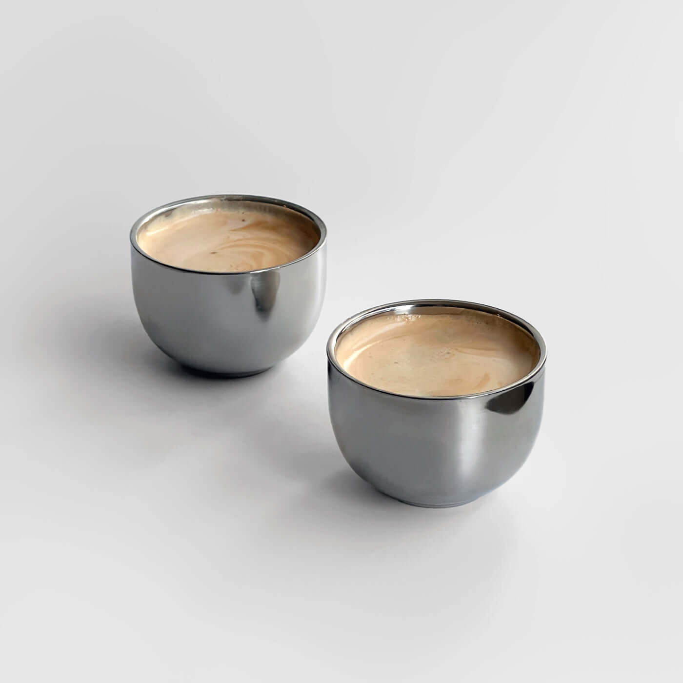 Glossy stainless steel Venice mirror cups with saucer and spoon, perfect for an elegant coffee experience.