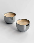 Glossy stainless steel Venice mirror cups with saucer and spoon, perfect for an elegant coffee experience.