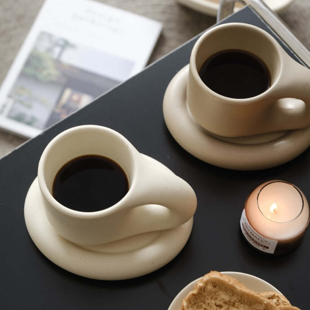 Artisan Nordic chubby mugs on plates with coffee and candle, showcasing minimalist clay design and free shipping promotion.