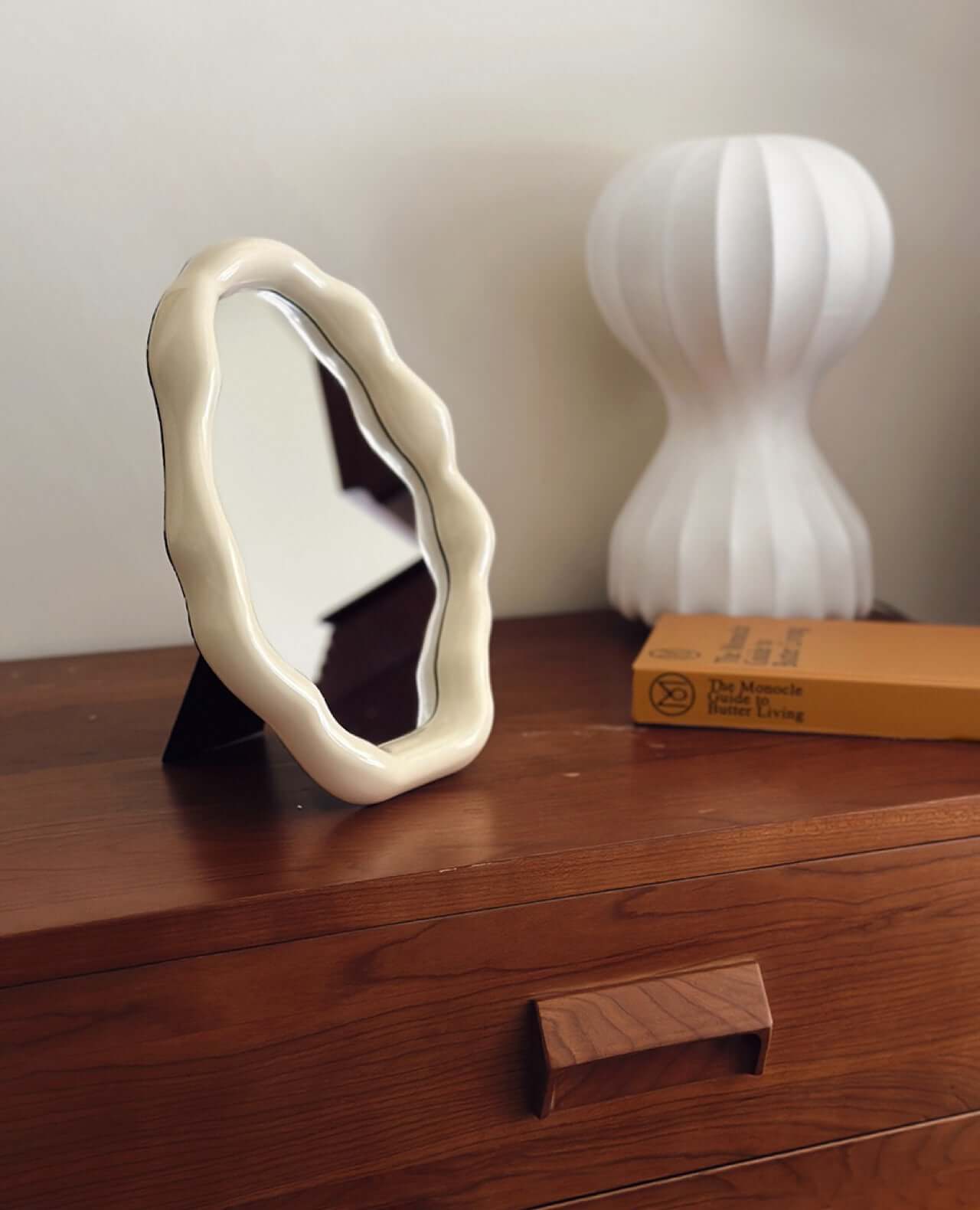 Nordic cloud-shaped vanity mirror on wooden dresser with a modern lamp and book, offering free shipping. Size: 27x20cm.