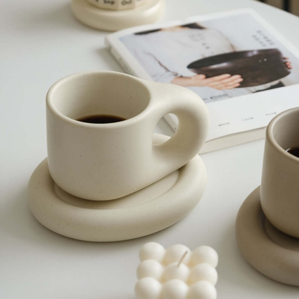 Nordic Artisan Chubby Mug and Plate showcasing minimalist design against a cozy backdrop with a book and candles.