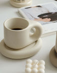 Nordic Artisan Chubby Mug and Plate showcasing minimalist design against a cozy backdrop with a book and candles.