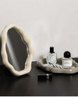 Nordic cloud-shaped vanity mirror with elegant frame on table, featuring perfumes and cosmetics, size 27x20cm.