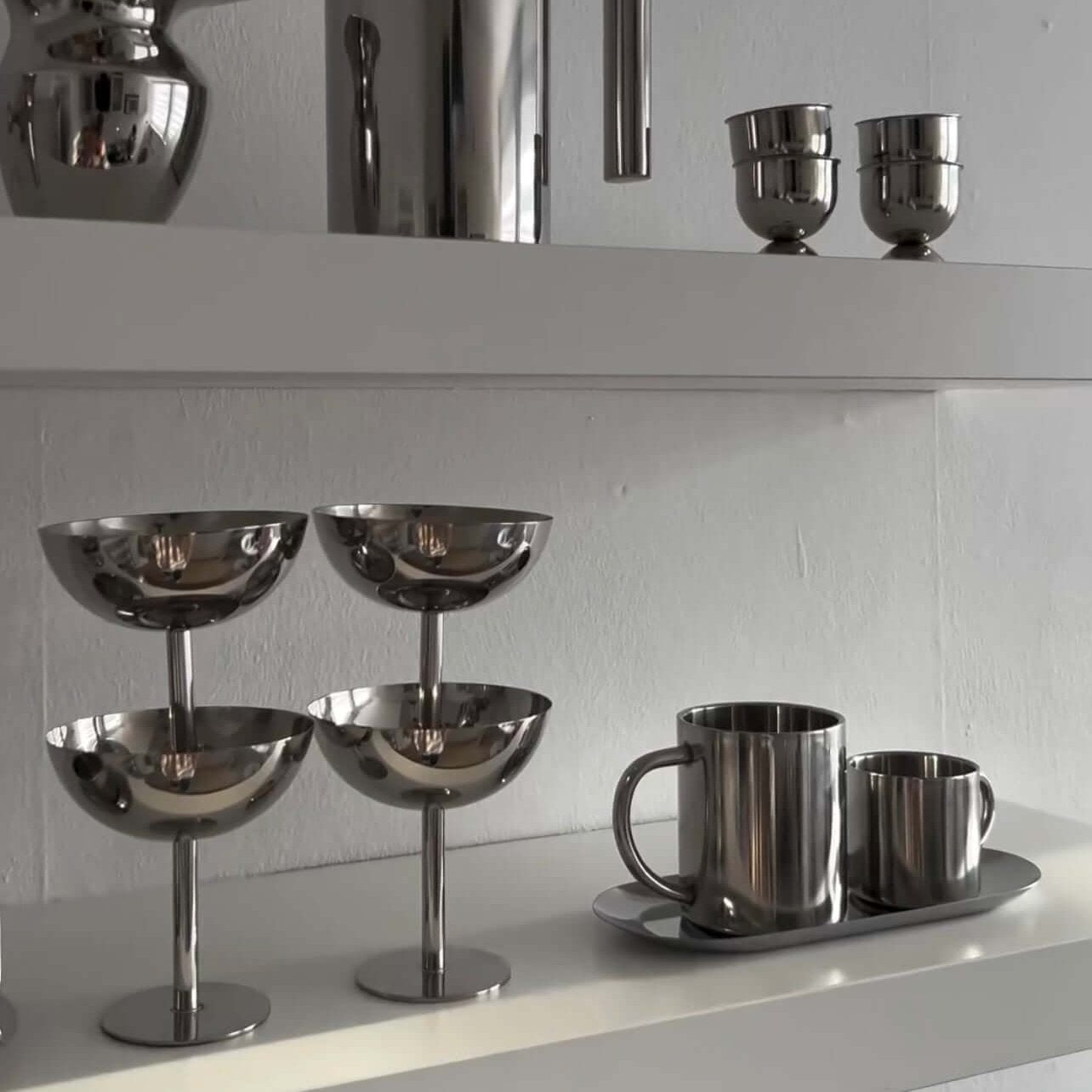 Minimalism stainless steel ice cream cups on shelf, alongside other sleek metal kitchenware, showcasing elegant design and sophistication.